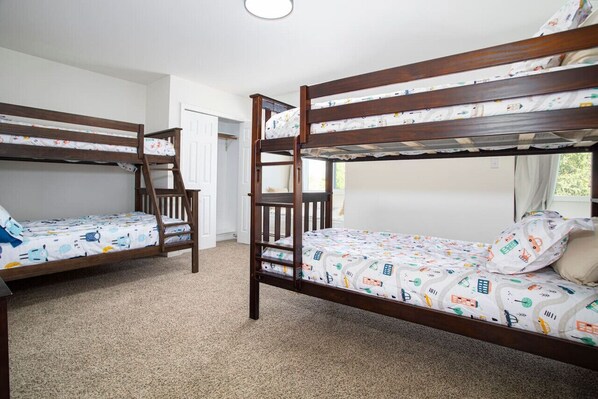 A room with two bunk beds, carpeted floor, and a window with curtains.