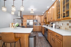 A modern kitchen with wooden cabinets, stainless steel appliances, and pendant lighting.