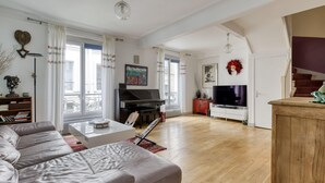 Ein geräumiges Wohnzimmer mit einer Couch, einem Couchtisch, einem Fernseher und einer Treppe.