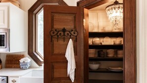 Uma cozinha com porta de madeira, janela e lustre.