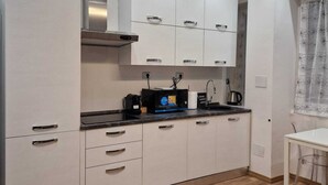 A modern kitchen with white cabinets, a black countertop, and a coffee machine. - Canova Accogliente Casa Vacanze - Affari (Milano)