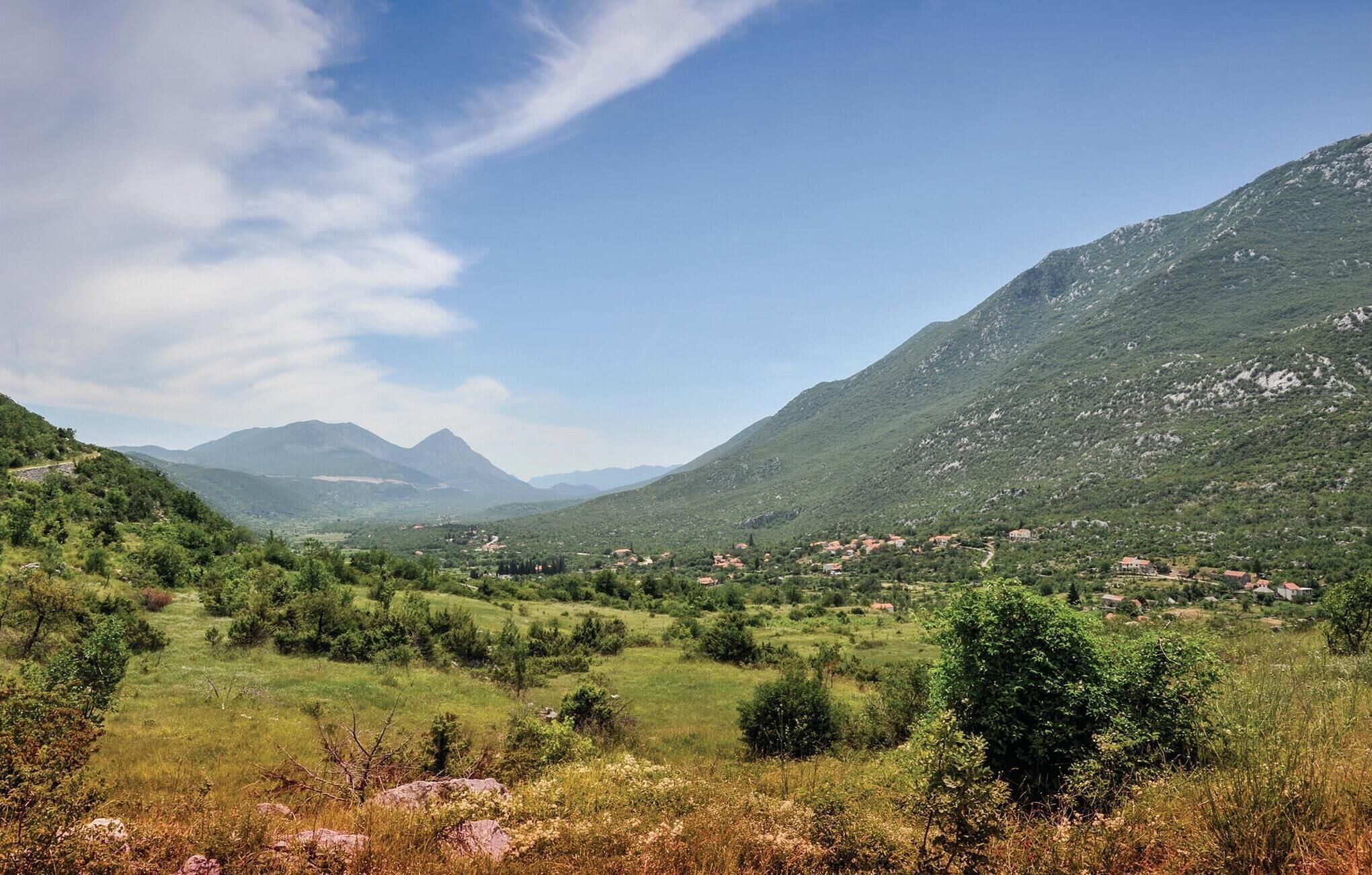 A mountainous landscape with a valley and scattered houses.