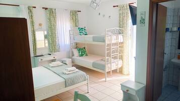 A bedroom with a bunk bed, a desk, a chair, and a small table.