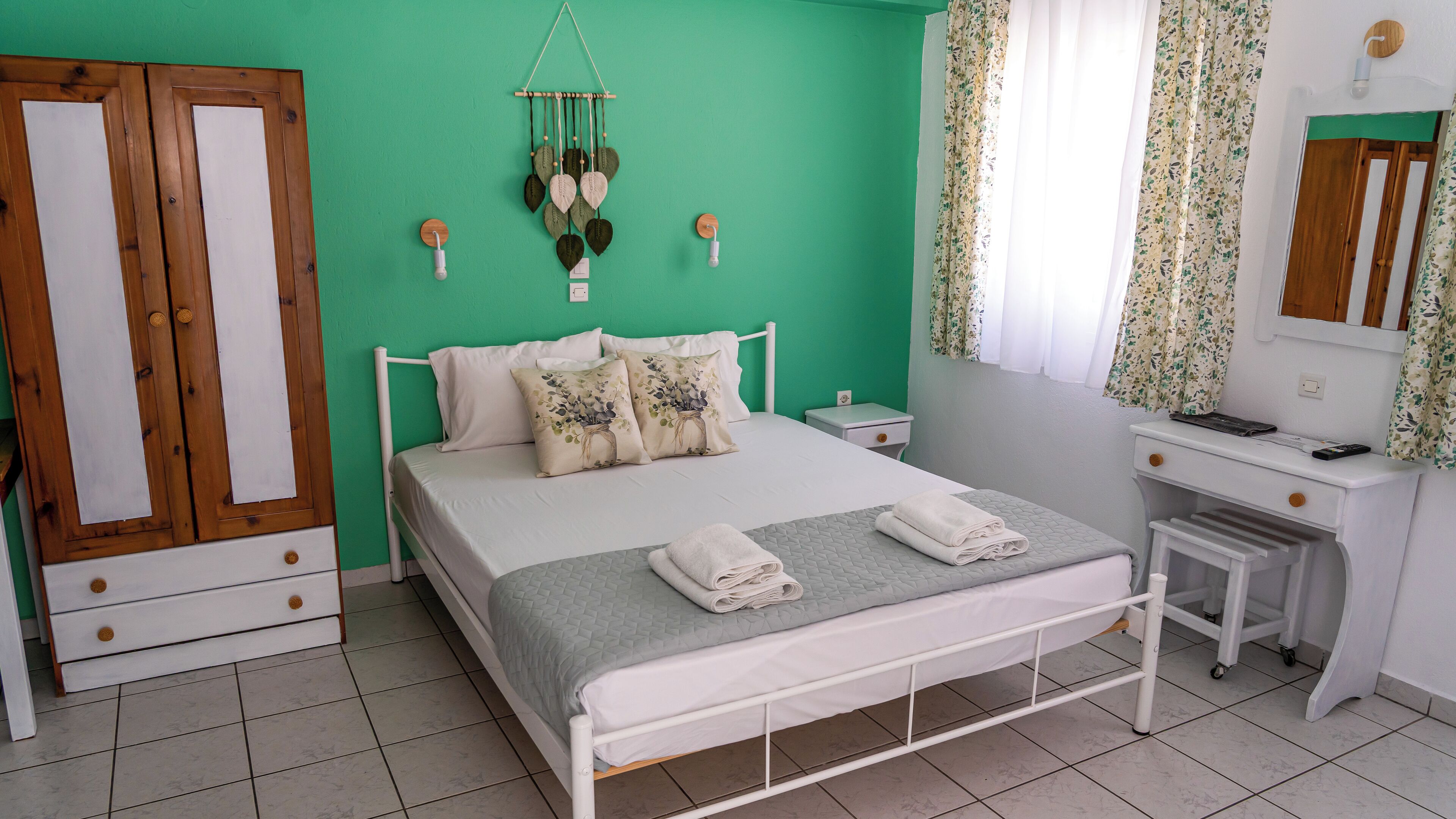 A bedroom with a bed, a desk, a wardrobe, and a wall-mounted decoration.