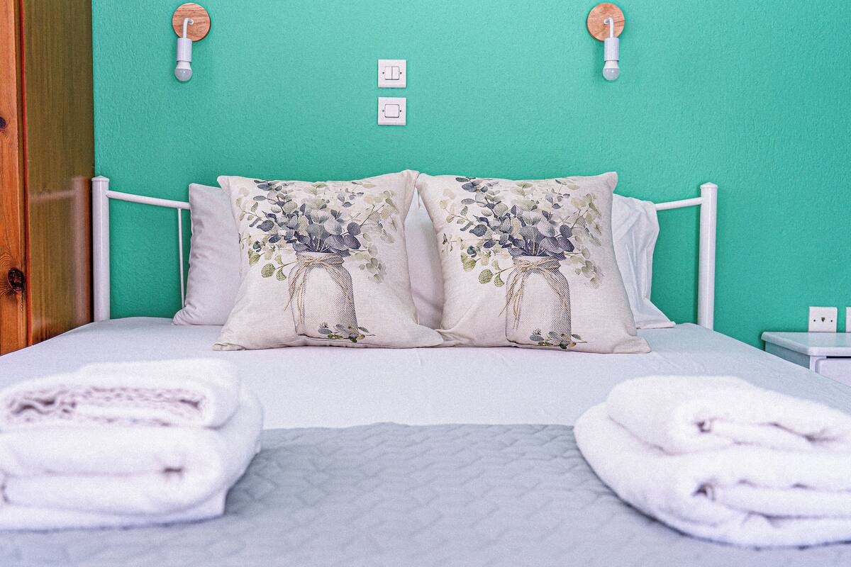 A bed with two pillows, a bedside table, and a wall-mounted light fixture.