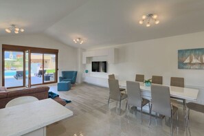 Un vaste espace de vie comprenant une table à manger, des chaises, un canapé et un téléviseur fixé au mur.