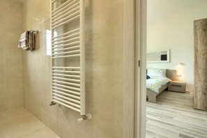 Un baño moderno con un toallero blanco y una zona de ducha visible.