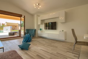 A modern living room with a flat-screen TV mounted on the wall, a sofa, a chair, and a coffee table. - Villa Markulin Comfortable holiday residence (Pula)