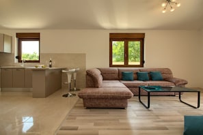 A modern living room with a sectional sofa, a coffee table, and a kitchen area with a bar. - Villa Markulin Comfortable holiday residence (Pula)