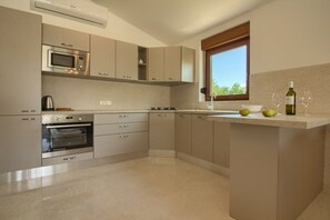 A modern kitchen with built-in appliances, a window, and a countertop with a bottle and glasses.