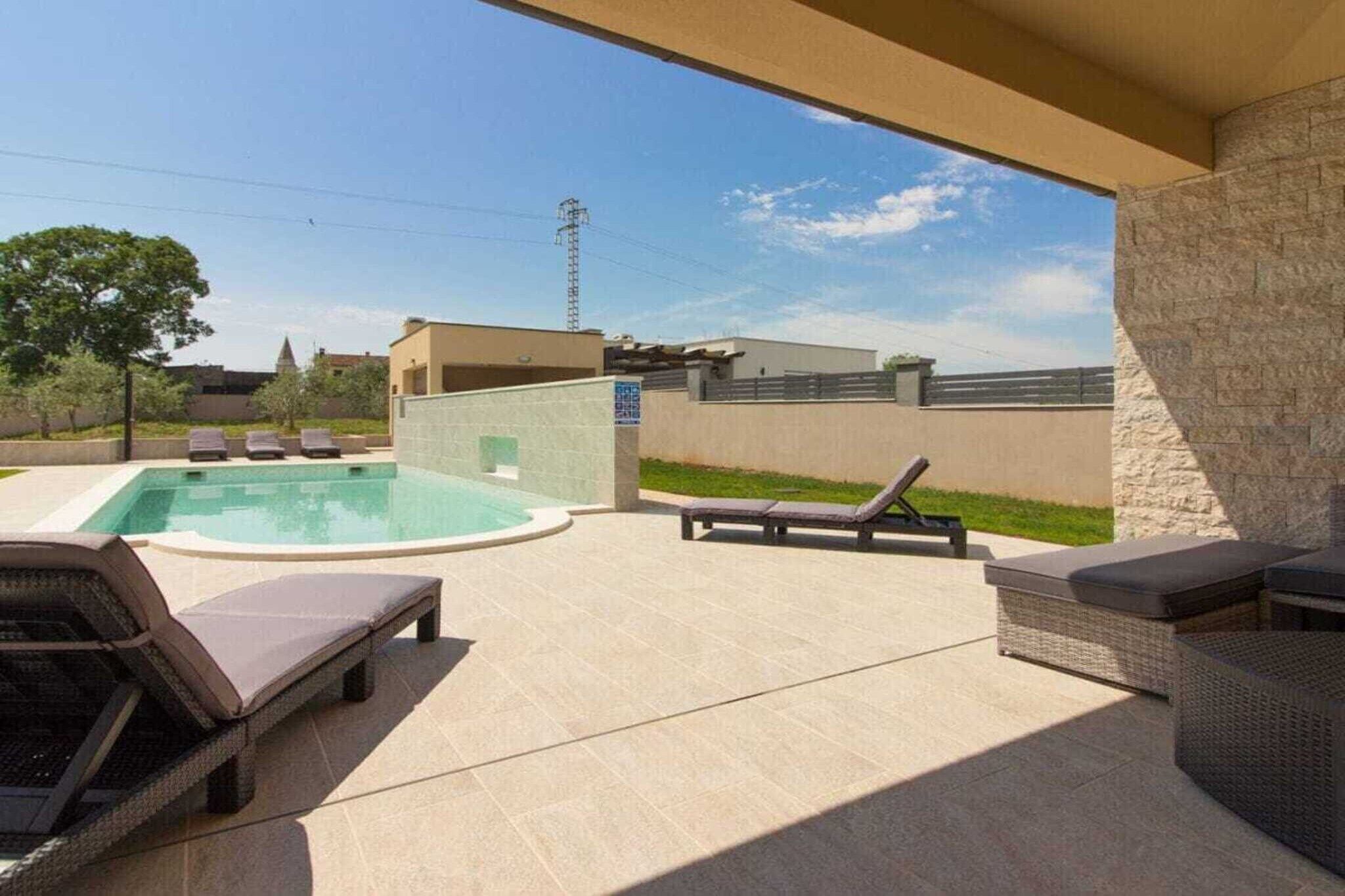 A pool area with lounge chairs and a hot tub.