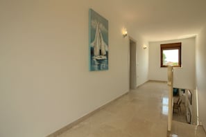 A hallway with a painting of a sailboat on the wall, a door at the end, and a window with a view of the outside. - Villa Markulin Comfortable holiday residence (Pula)