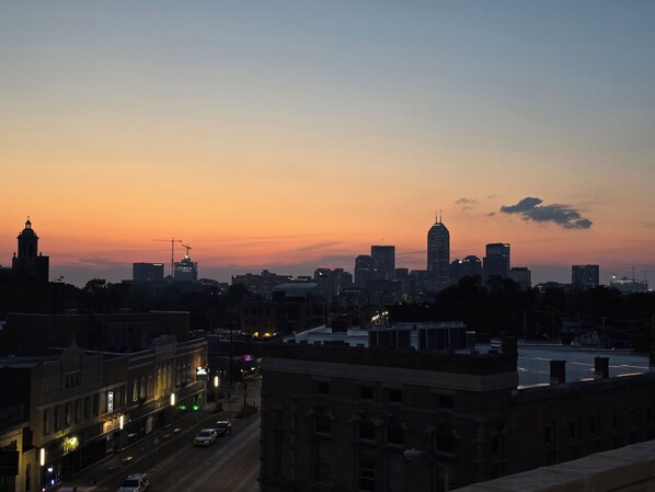 A city skyline at dusk with buildings silhouetted against a sunset sky.