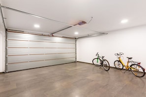 A garage with a closed garage door, two bicycles, and a ceiling light fixture.