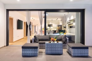 A modern living room with a sofa set, two ottomans, and a coffee table.