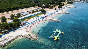 Ett flygbildsbild av ett kustområde med en strand, en parkeringsplats och en stenstrand.