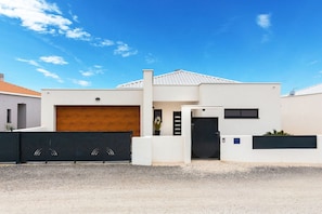 A modern two-story house with a garage, a wooden door, and a black gate.