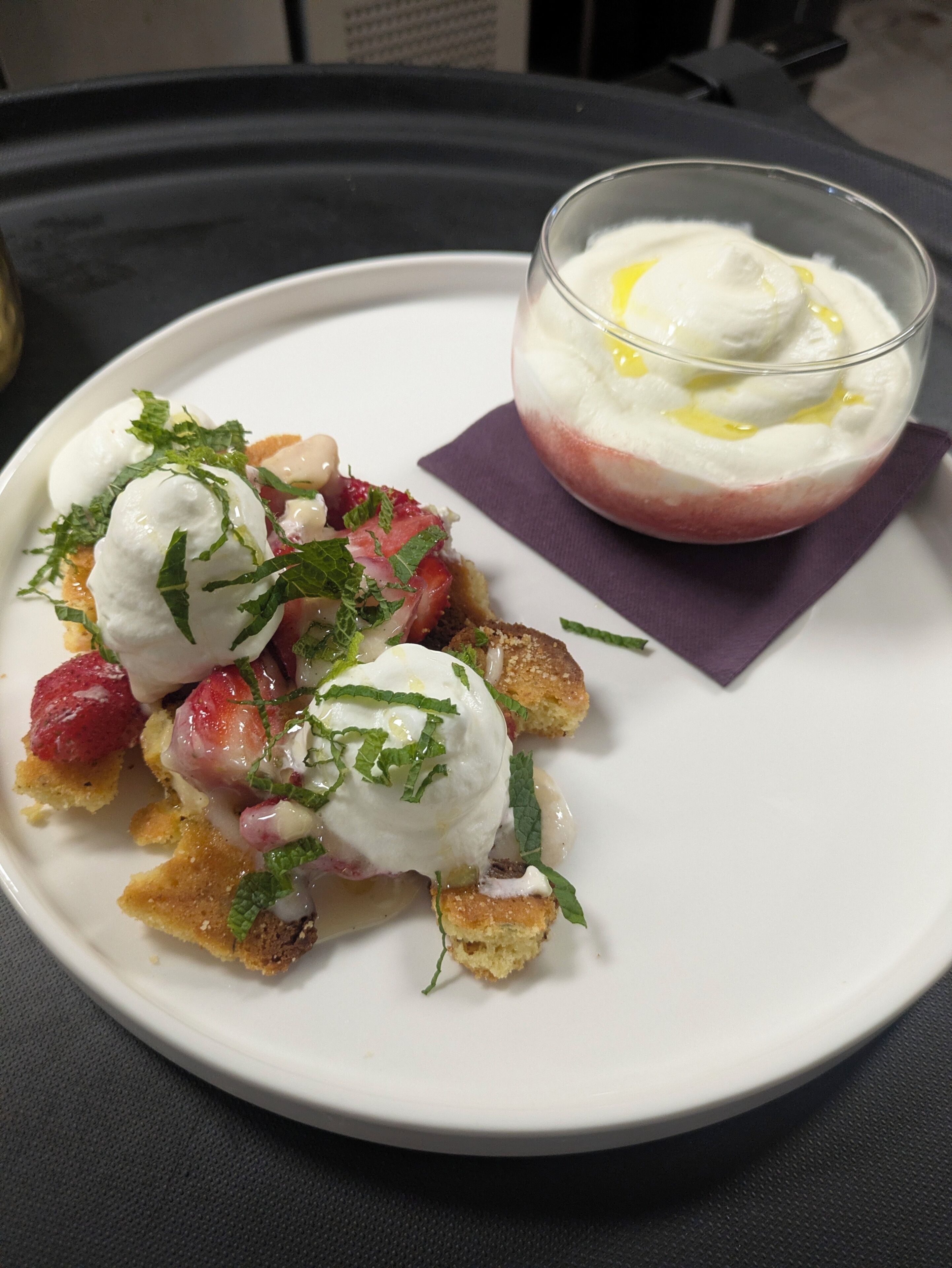 Plato de postre con huevos pochados, fresas y menta sobre un plato blanco.