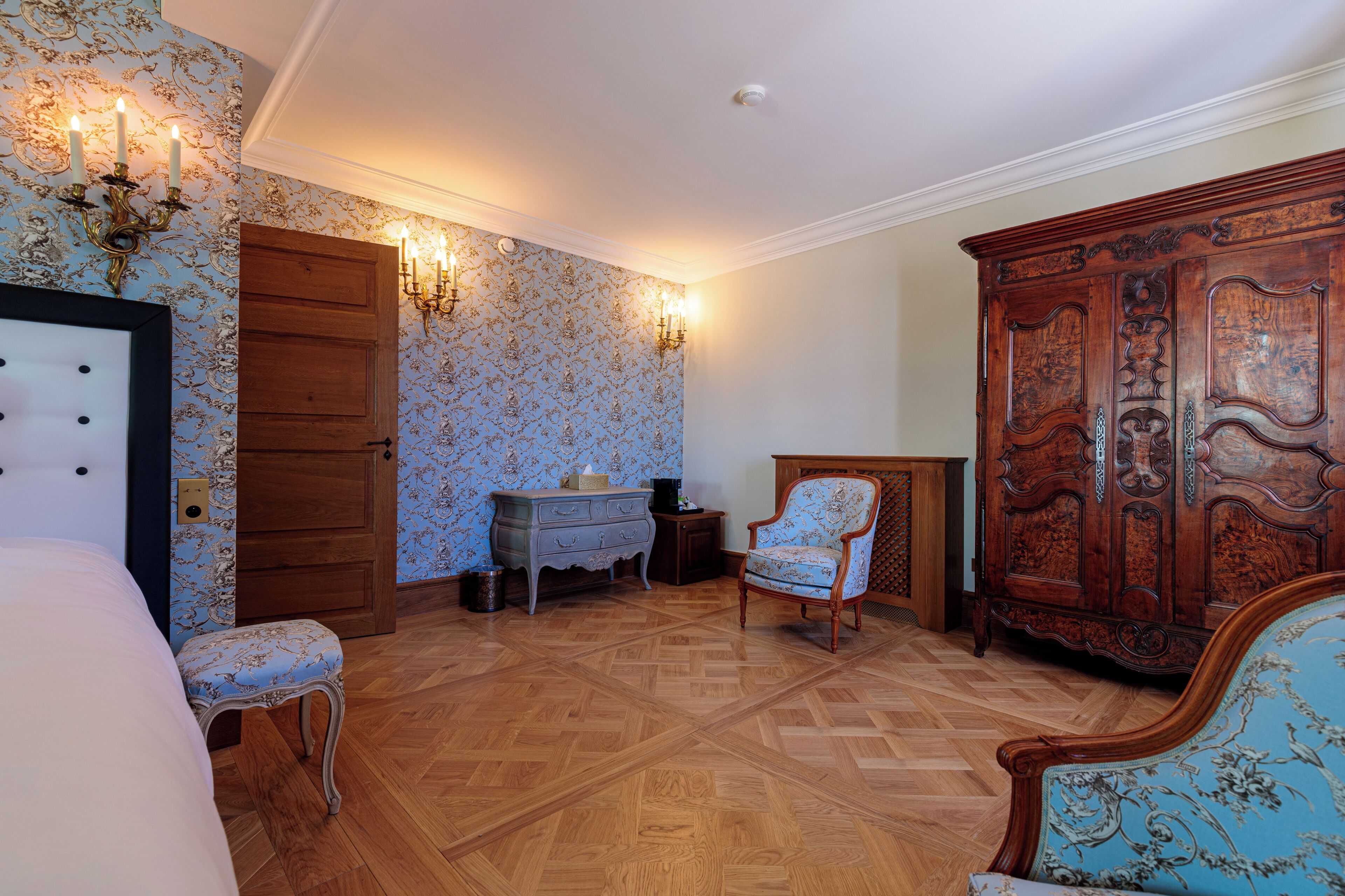 Un dormitorio con piso de madera, una cama, un tocador, una silla y un armario.