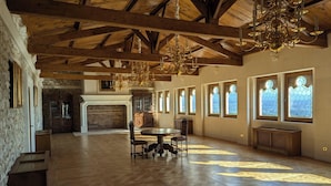 Un'ampia stanza con alto soffitto in legno, un camino e grandi finestre con vetrate colorate.