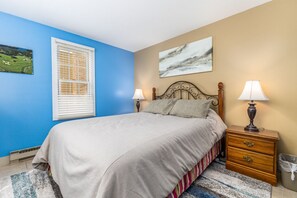 A bedroom with a bed, two bedside tables with lamps, a window with blinds, a painting on the wall, and a rug. - Galena Settlement Getaway (Galena)