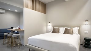 Une chambre moderne avec un grand lit, un bureau avec une chaise et un tabouret.