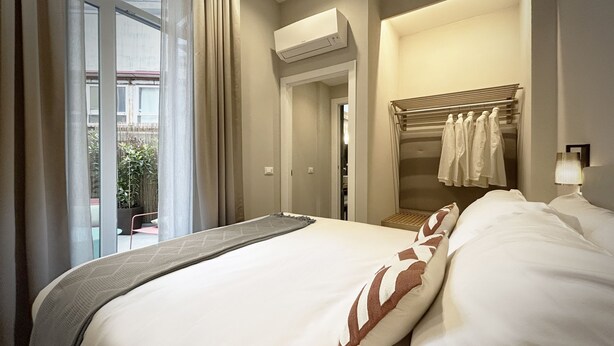 Une chambre d’hôtel avec un grand lit, un dressing et une vue sur l’extérieur.