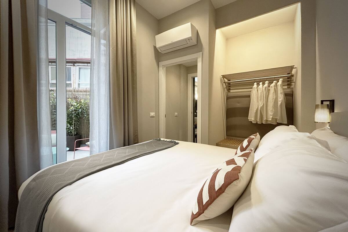 Une chambre d’hôtel avec un grand lit, un dressing et une vue sur l’extérieur.