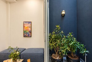 A room with a blue wall, a framed painting, a potted plant, and a seating area with cushions. - Nexus House Cay Diep - Near Independence Palace (Ho Chi Minh City)