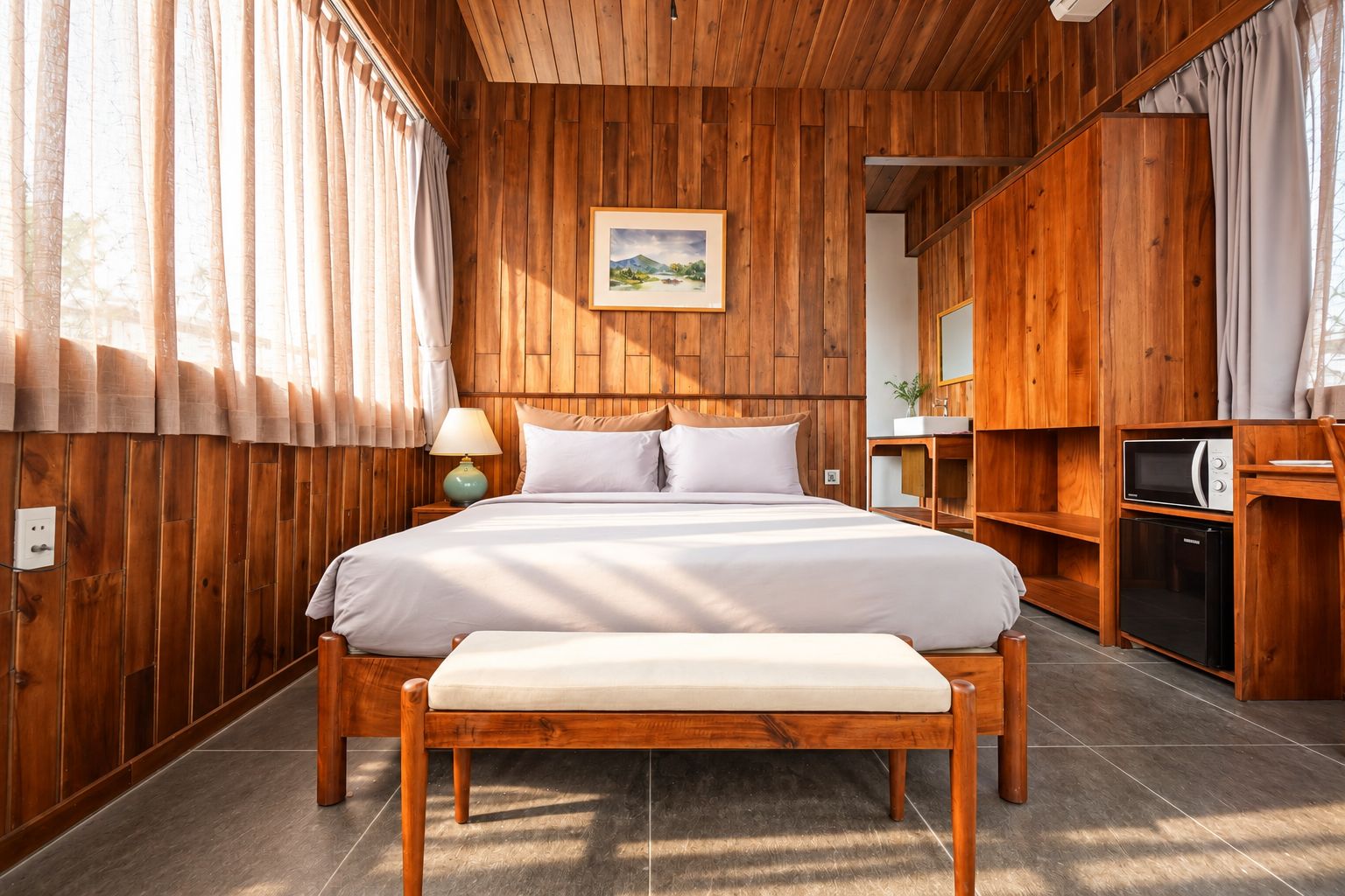 Una habitación con paneles de madera, con cama, mesita de noche, lámpara y microondas.