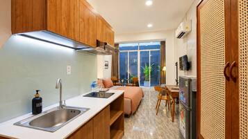 A modern kitchen with a built-in stove, a sink, and a refrigerator. There is a dining area with a table and chairs, and a sofa.