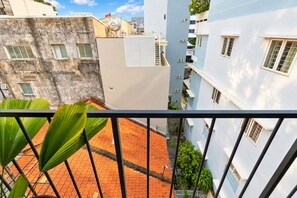 Un immeuble à plusieurs étages, doté de balcons, d’une cour dallée de tuiles rouges et d’un drapeau sur le toit.