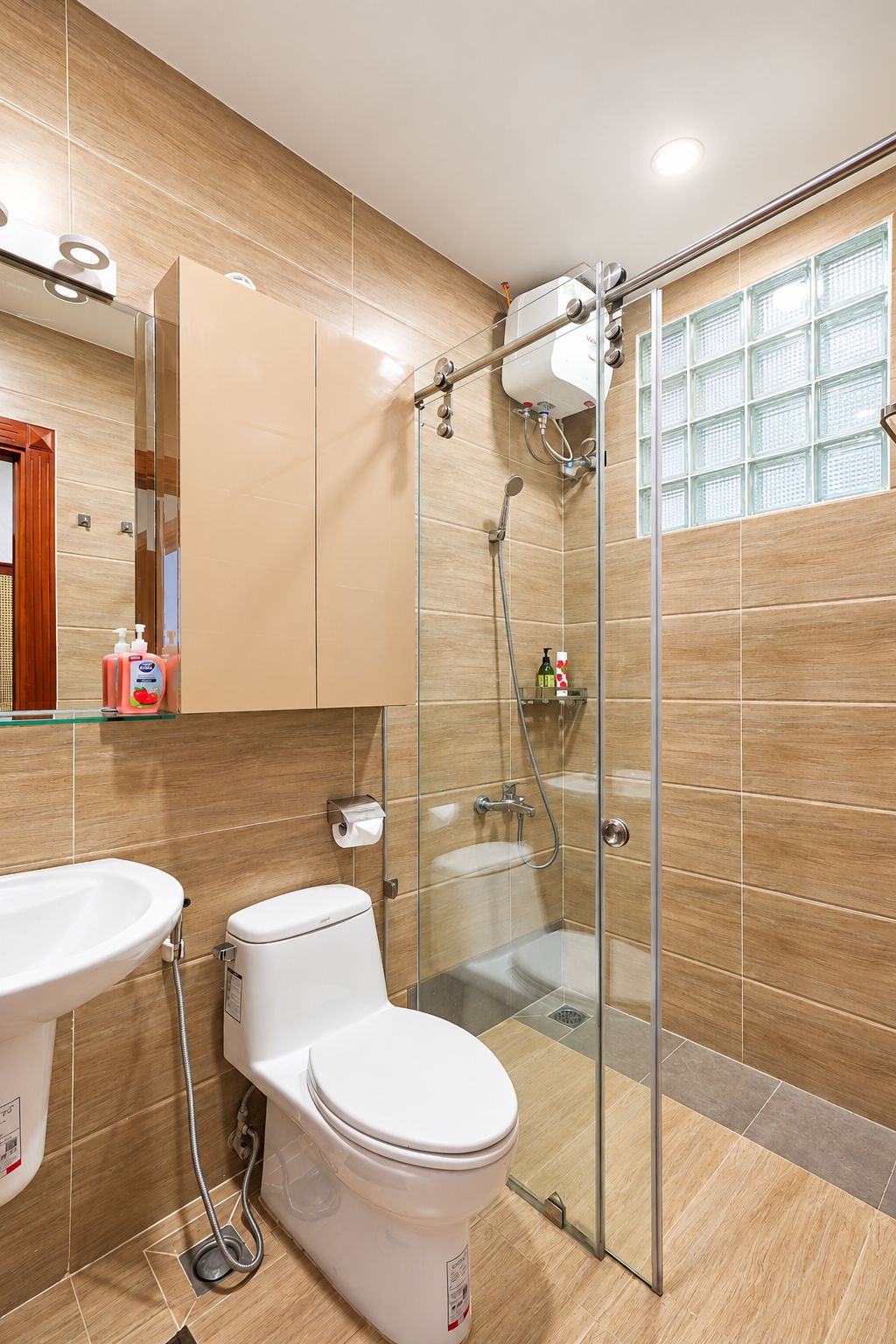 A modern bathroom with a glass shower enclosure, a toilet, and a sink.