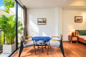 Una habitación de hotel moderna con sofá, dos sillones, una mesita, lámpara y cama.