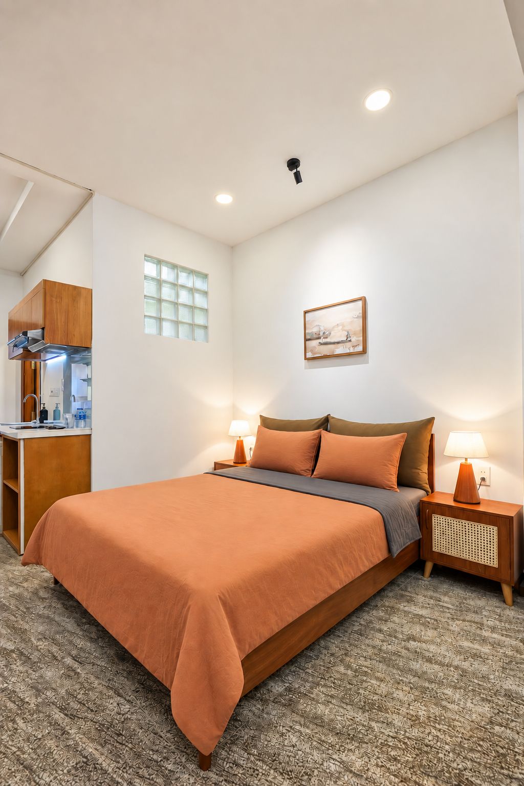 A hotel room with a bed, bedside lamps, a small table, a mirror, and a window.