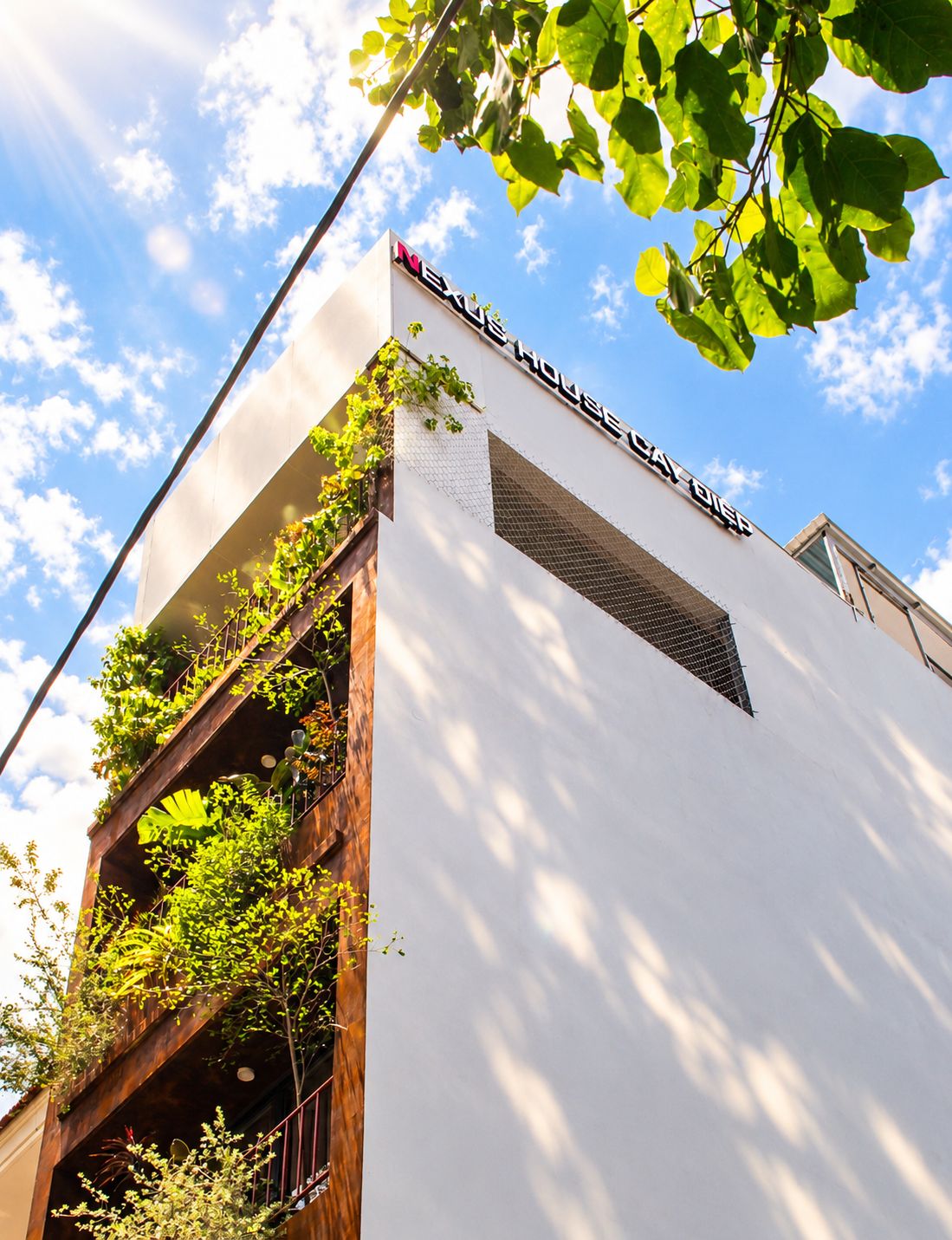 Un edificio moderno con fachada blanca y un cartel que dice 'NEXUS HOUSE'.