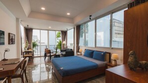 Habitación de hotel moderna con una cama grande, un escritorio y un balcón con vistas a la ciudad.