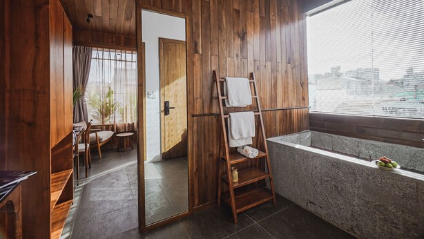 Un baño con acabados de madera, una bañera, una escalera de madera y un espejo.