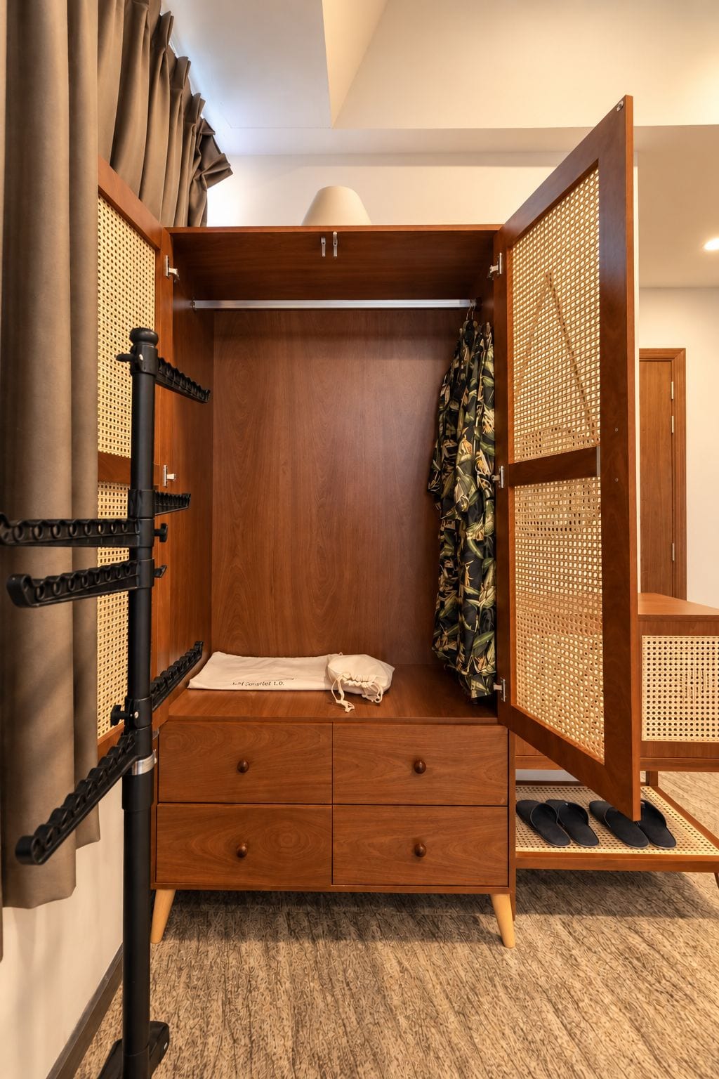 A wooden wardrobe with a hanging space, a small bedside table, and a pull-out drawer.