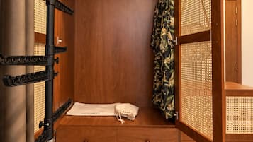 A wooden wardrobe with a hanging space, a small bedside table, and a pull-out drawer.
