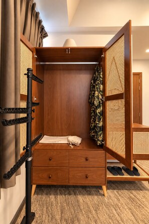Une armoire en bois avec un espace pour suspendre les vêtements, une petite table de chevet et un tiroir coulissant.