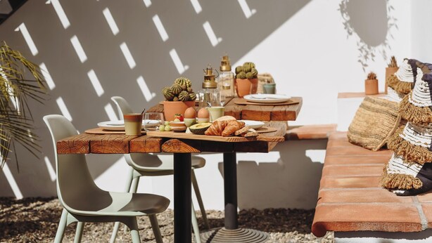 A breakfast table set with eggs, bread, and fruit, surrounded by chairs and a bench. - Finca Viva la Vida (Álora)