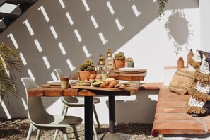 A breakfast table set with eggs, bread, and fruit, surrounded by chairs and a bench. - Finca Viva la Vida (Álora)