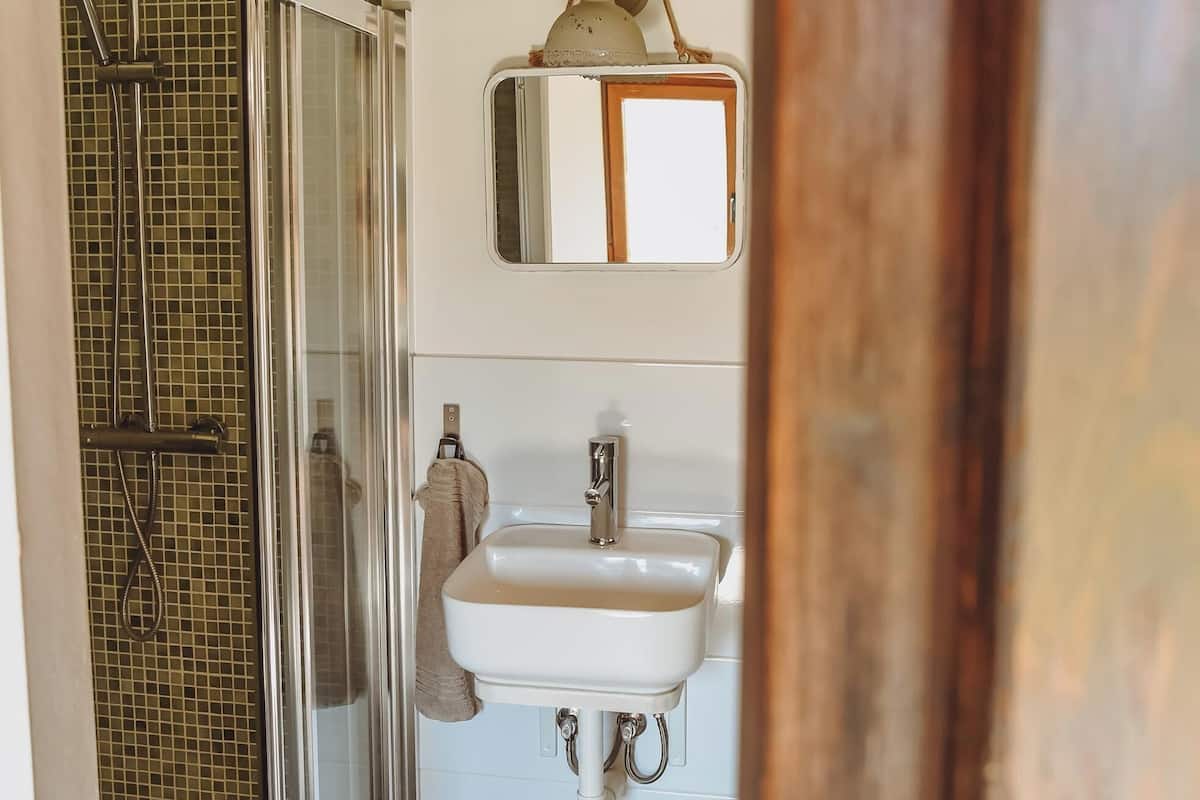 A bathroom with a glass-enclosed shower, a white sink, and a mirror above it.