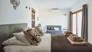 A hotel room with a large bed, a sofa, a wall-mounted air conditioner, and a window with curtains. - Finca Viva la Vida (Álora)