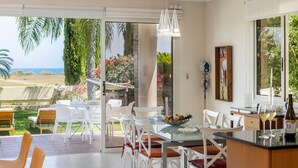 Una cocina moderna con una mesa de vidrio, sillas blancas y vistas al mar.