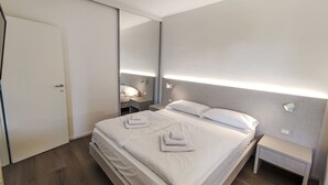 Una camera d'albergo moderna con un letto grande, comodini, uno specchio e un armadio.