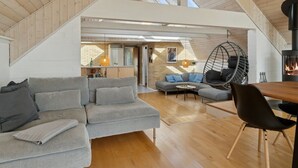 A spacious loft with a high ceiling, a dining area, a kitchen, and a cozy seating area with a hanging chair. - "Jolanta" - 20m from the sea by Interhome (Malling)