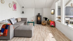 Una sala moderna con un sofá seccional gris, una mesita, una chimenea y un ventanal grande.
