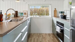 Una cocina moderna con encimera de madera, electrodomésticos de acero inoxidable y una ventana con vistas a árboles.